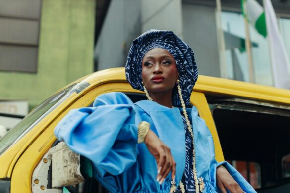 A woman in a blue outfit leaning from a yellow bus in Lagos